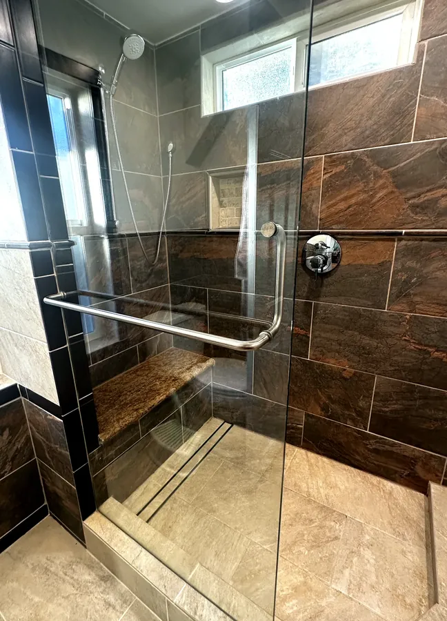 Close-up of chrome shower door hardware and glass edge on a Tri-Cities frameless enclosure